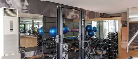 Un gimnasio con un rack para sentadillas, pesas libres y pelotas de ejercicio.