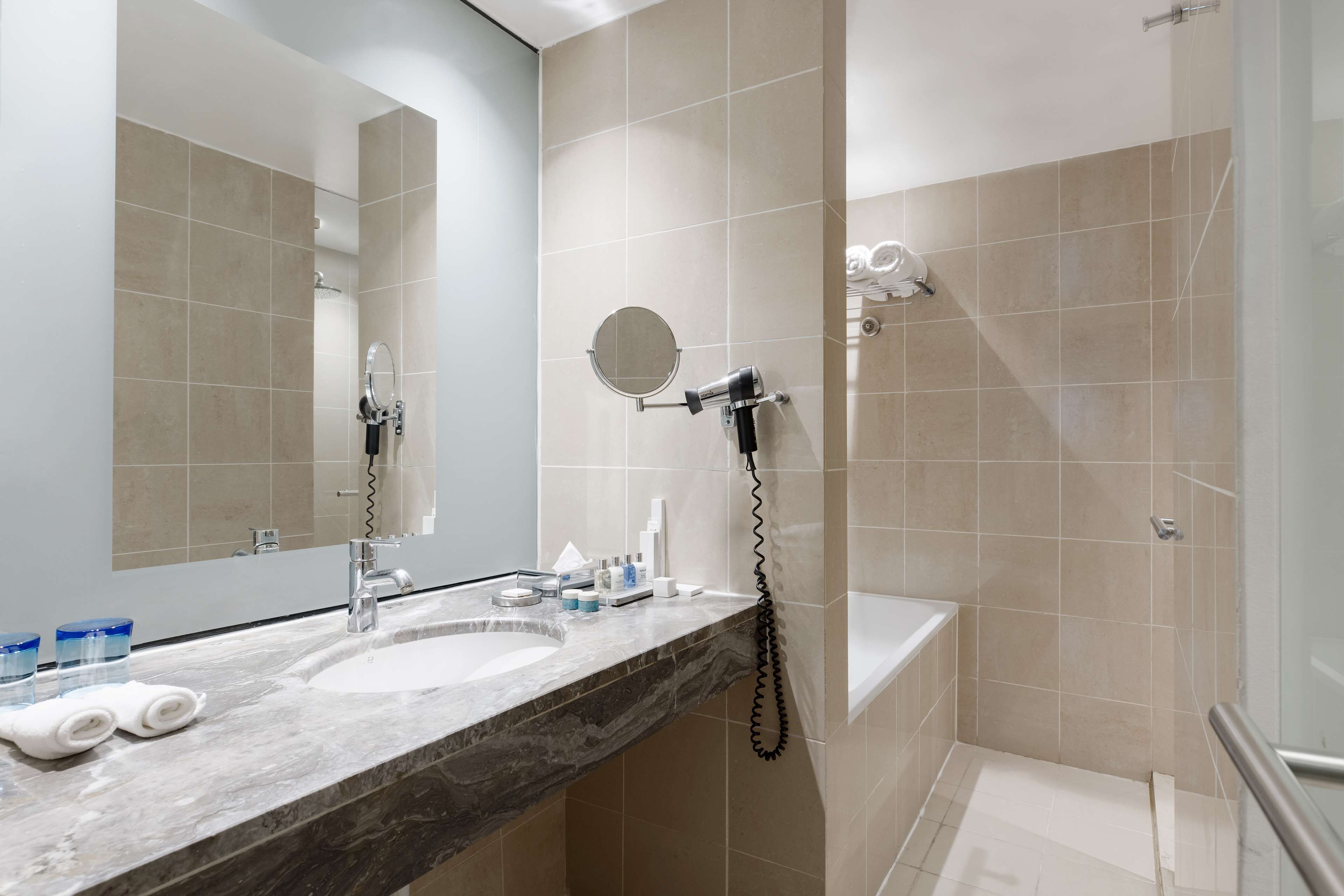 Een badkamer met twee wastafels, een spiegel, een haardroger en een douche.