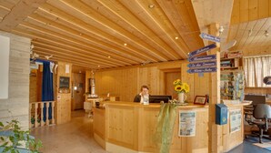 Un comptoir d’accueil en bois, agrémenté de panneaux d’orientation, une réceptionniste et un rideau bleu en arrière-plan.