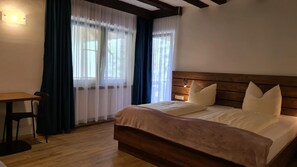 Ein Schlafzimmer mit einem Holzkopfteil, einem Bett mit weißer Bettwäsche, einem Holztisch und einem Stuhl.
