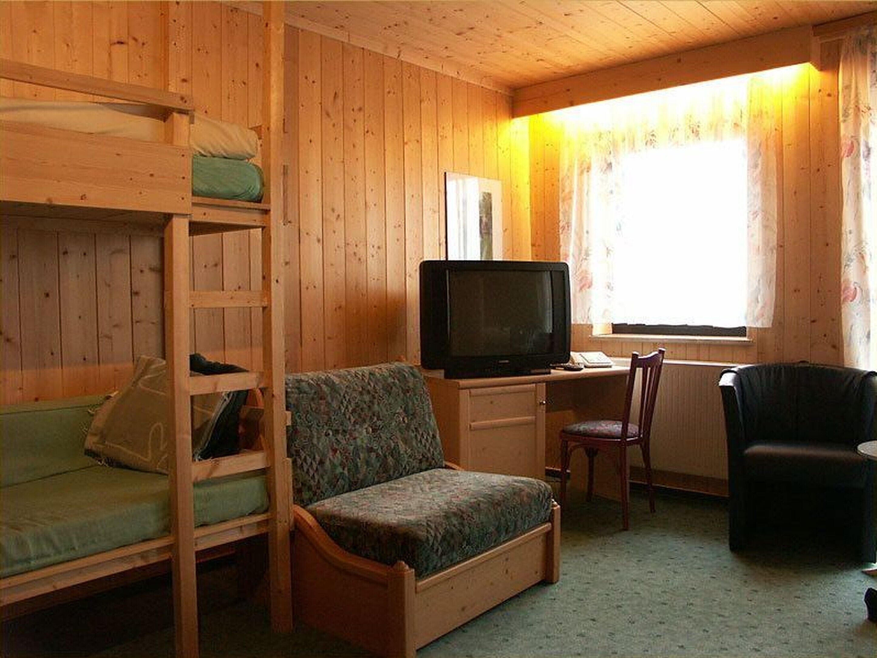A cabin with bunk beds, a television, a desk, and a chair.