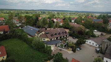 A residential area with houses, a large building with solar panels, and a view of a lake and hills.