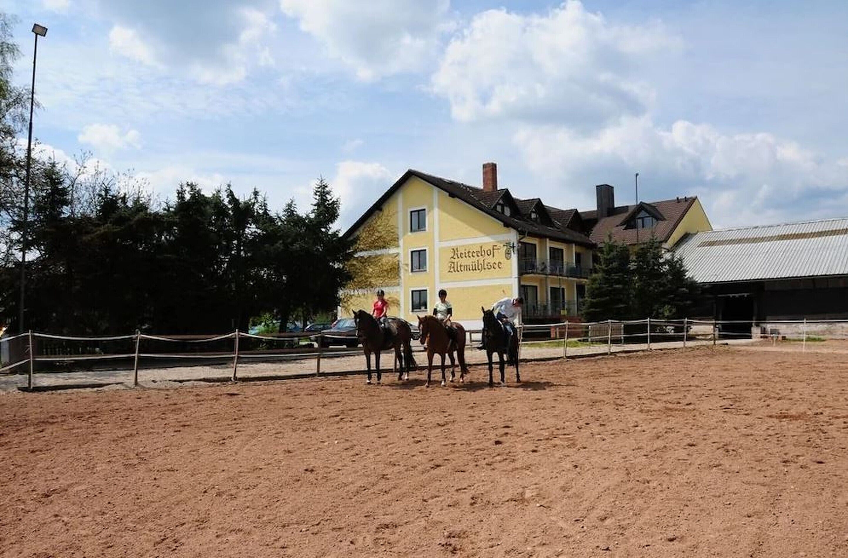 Eine Reitanlage mit einem gelben Gebäude im Hintergrund, auf dem "Heizebohf Altmühlesee" steht.
