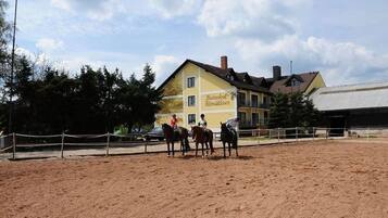Eine Reitanlage mit einem gelben Gebäude im Hintergrund, auf dem "Heizebohf Altmühlesee" steht.