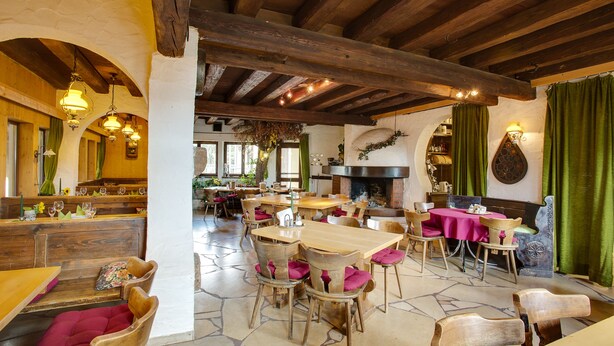 Un coin repas rustique avec des tables et des chaises en bois, un sol en pierre et une cheminée.