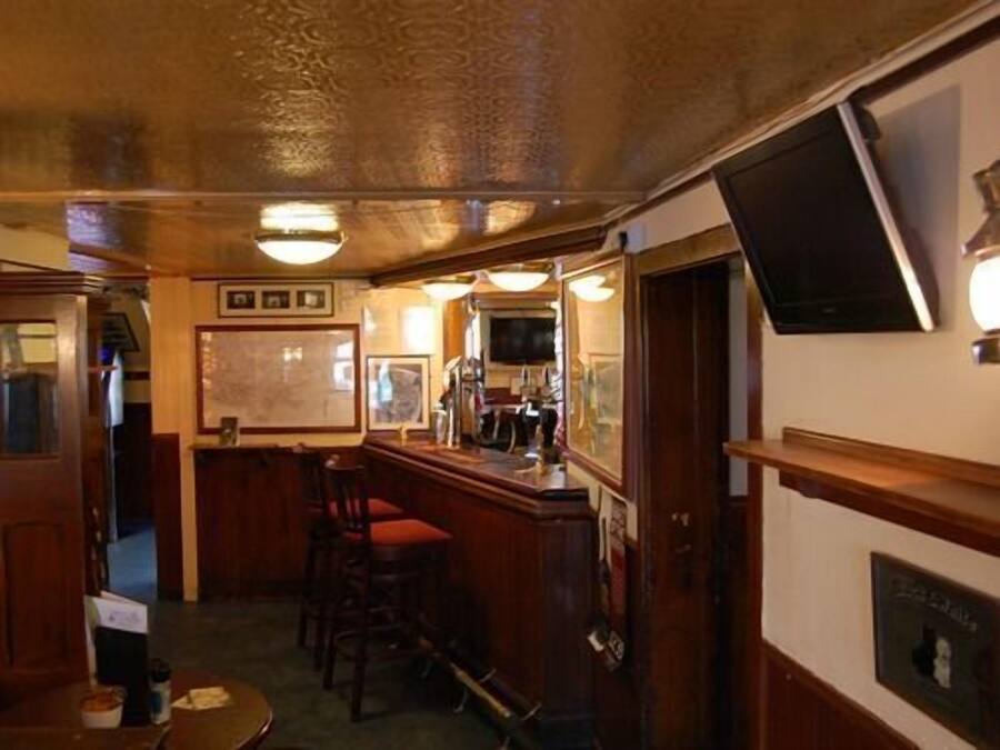 Et barområde med træmøbler, en bar og billeder i rammer på væggen.