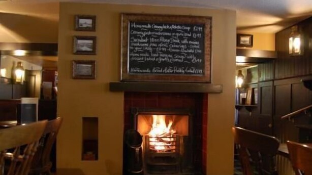 A cozy room with a fireplace, wooden furniture, and a chalkboard menu. - Fisherman's Tavern Hotel - Inn by Greene King Inns (Dundee)