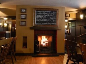 A cozy room with a fireplace, wooden furniture, and a chalkboard menu. - Fisherman's Tavern Hotel - Inn by Greene King Inns (Dundee)