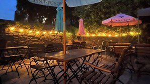 An outdoor seating area with tables and chairs, umbrellas, and string lights. - Fisherman's Tavern Hotel - Inn by Greene King Inns (Dundee)