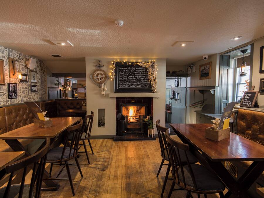 Un restaurante acogedor con chimenea, muebles de madera y una pared de piedra decorada con cuadros.
