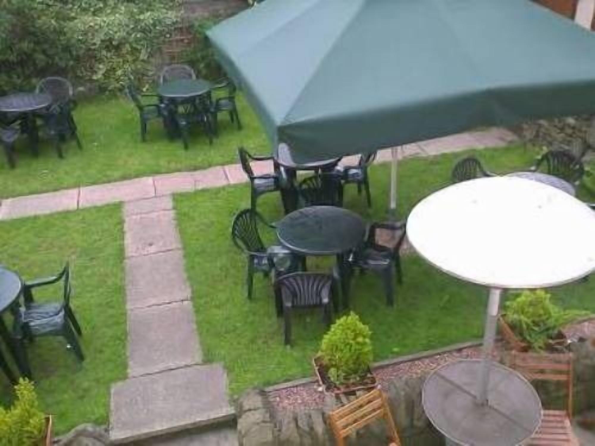 Een buitenterras met meerdere ronde tafels en stoelen, waarvan sommige onder parasols.