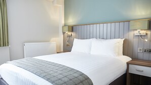 A hotel room with a large bed, a bedside table, a nightstand, a wall-mounted lamp, and a radiator. - Fisherman's Tavern Hotel - Inn by Greene King Inns (Dundee)