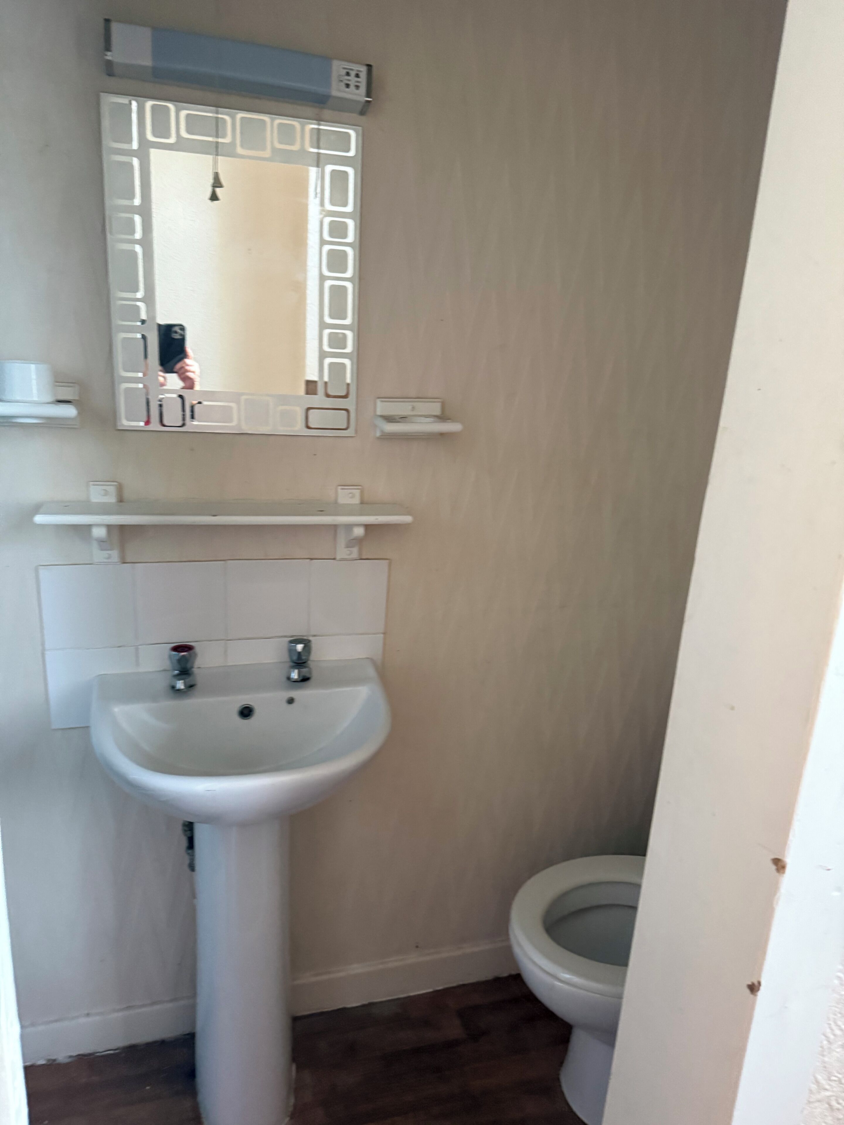 A bathroom with a white sink, mirror, and toilet.