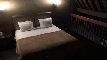Una camera da letto con un letto, due comodini, un tavolino e una culla in legno.