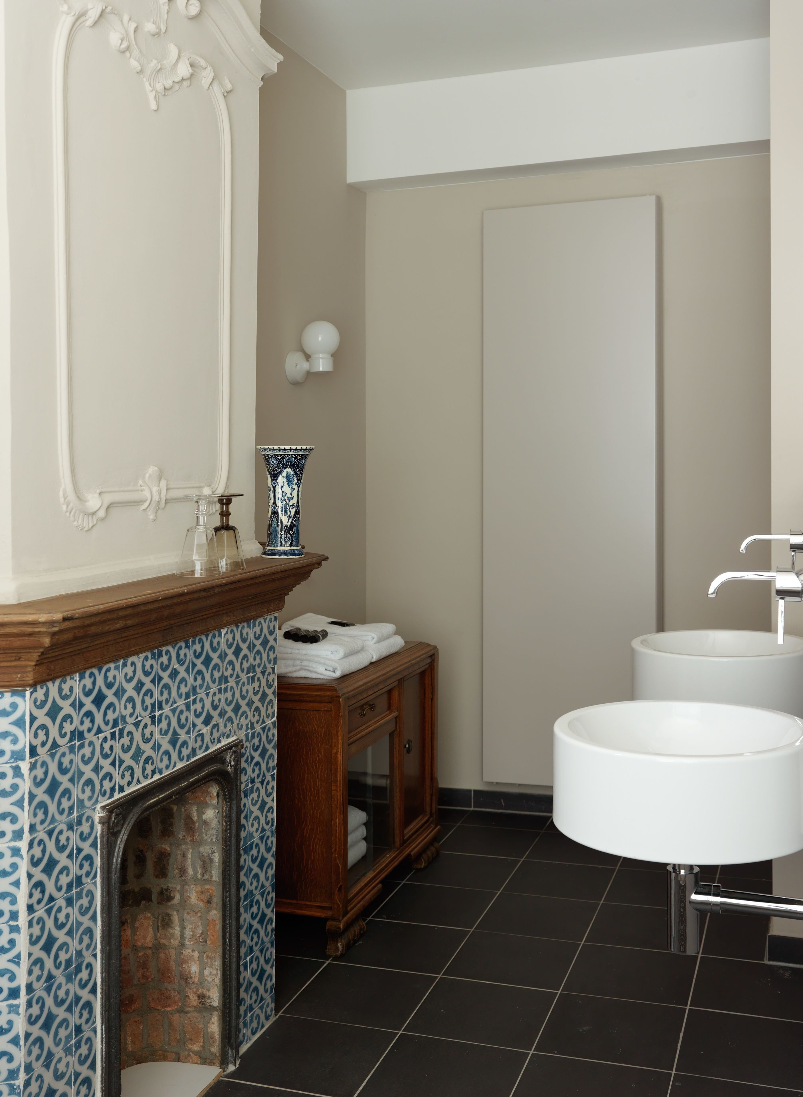 A bathroom with a tiled floor, a wooden cabinet, a white sink, and a mirror with decorative molding.
