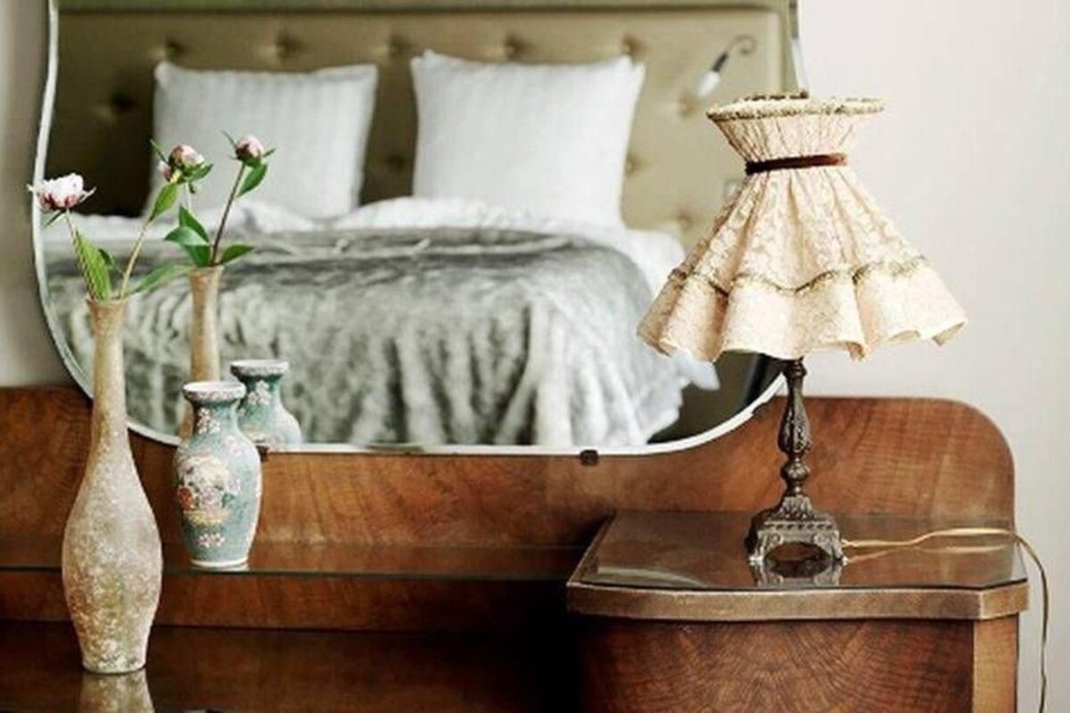 Ein Schlafzimmer mit Bett, Kommode, Spiegel und Lampe.