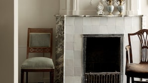 A fireplace with a tiled surround, two decorative vases, and a framed picture on the wall. - Boutique Hotel Grote Gracht (Maastricht)