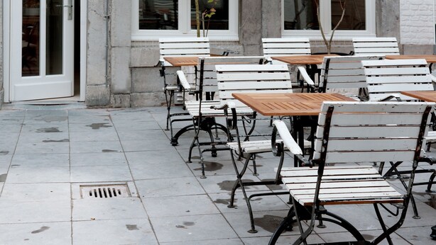 A row of white wooden tables and benches outside a building with white brick walls and large windows. - Boutique Hotel Grote Gracht (Maastricht)