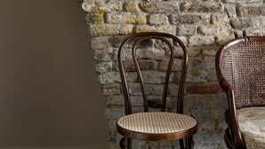 A room with a brick wall, two wooden chairs, and a small decorative item. - Boutique Hotel Grote Gracht (Maastricht)