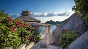 Una escalera de piedra que lleva a una construcción de techo de paja con vista al mar.