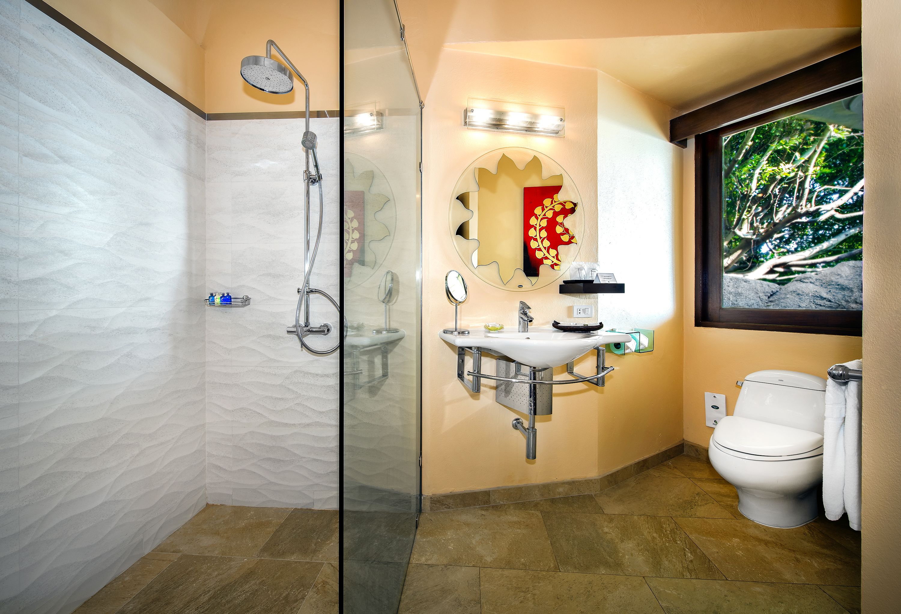 Un baño con ducha de vidrio, lavamanos con espejo e inodoro.