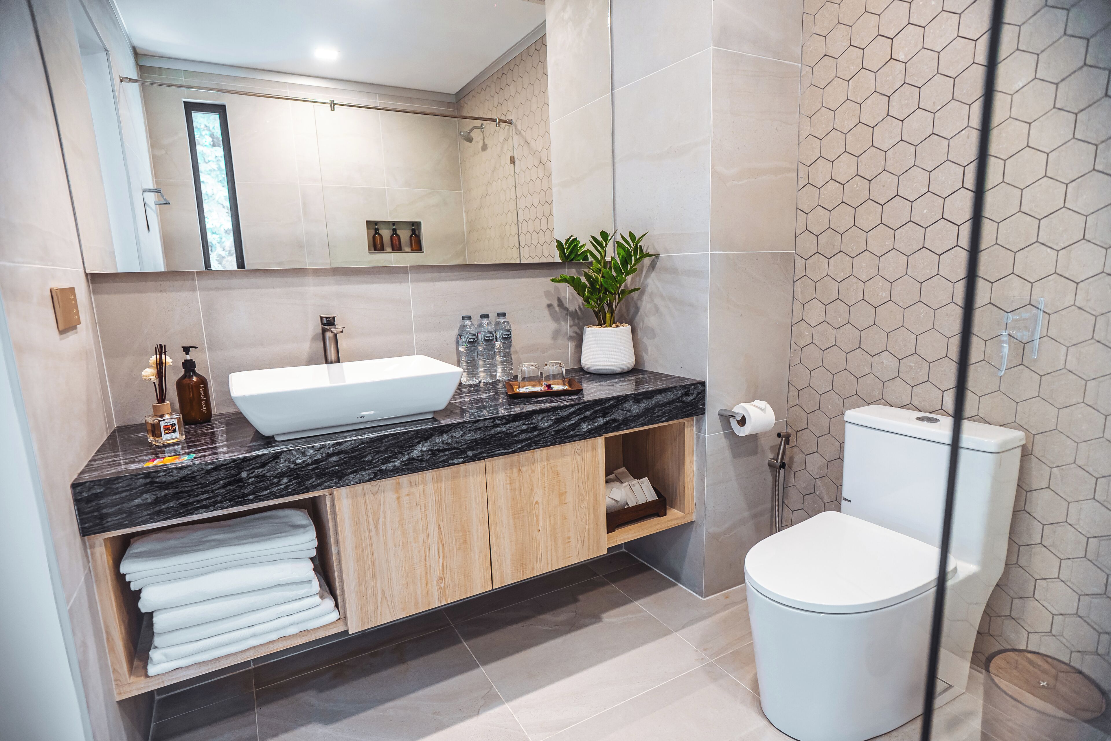 Un baño moderno con un lavamanos grande de color blanco, armarios de madera y un inodoro.