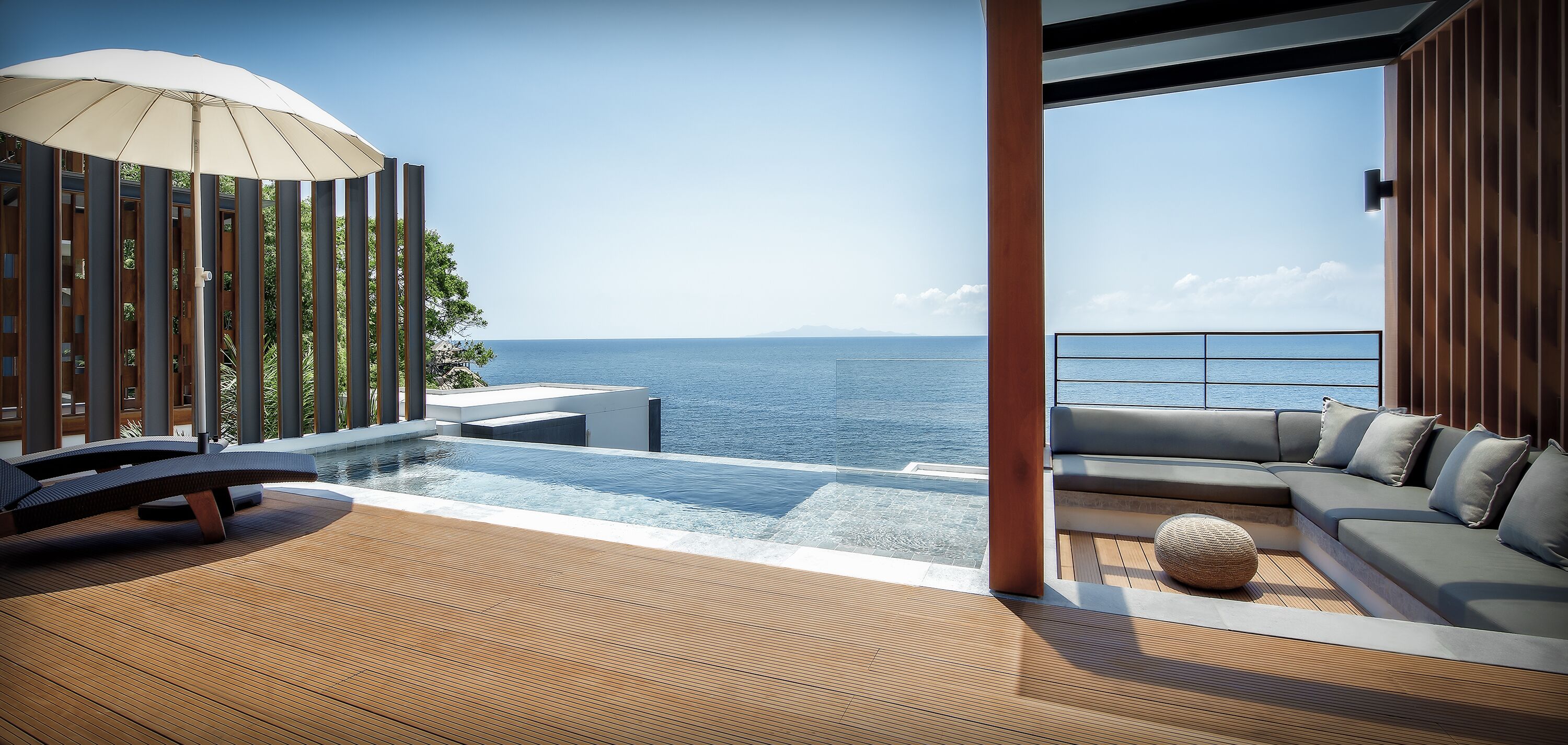 Un área de descanso al aire libre moderna con piscina, asientos y vistas al mar.