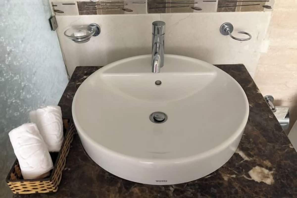 Une salle de bain avec un lavabo blanc, un robinet chromé et un comptoir en marbre.