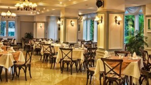 Una zona de dinar formal amb diverses taules i cadires, lluminàries penjants i aplics de paret.