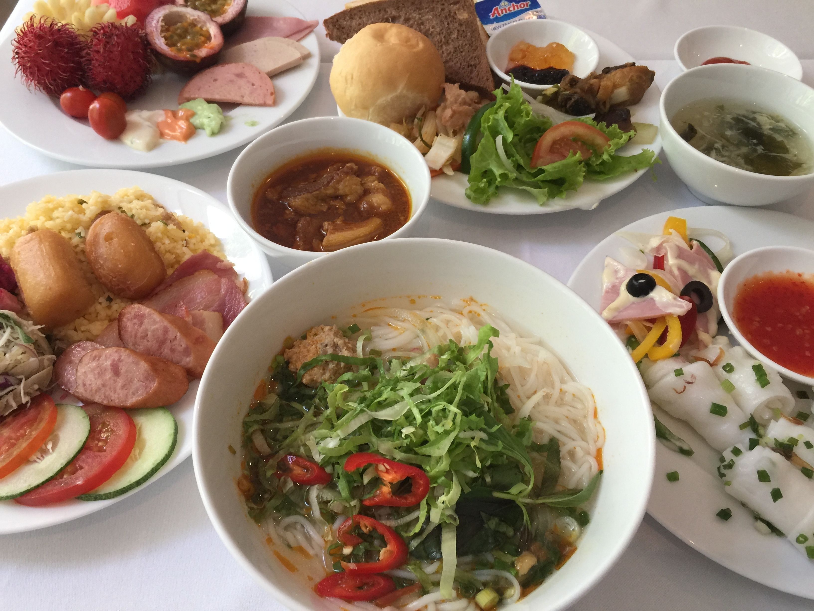 Diverses platillos, incloent un bol de sopa de noodles amb verdures, un plat amb botifarra i arròs, i diversos altres platillos amb diferents cobertures i salses.