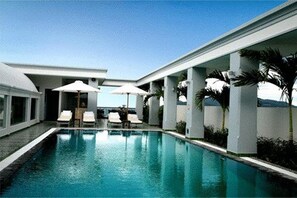 A modern pool area with clear blue water, white columns, and lounge chairs.