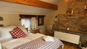 Une chambre à coucher avec un lit, une table de chevet, une cheminée en pierre et un plafond en bois.