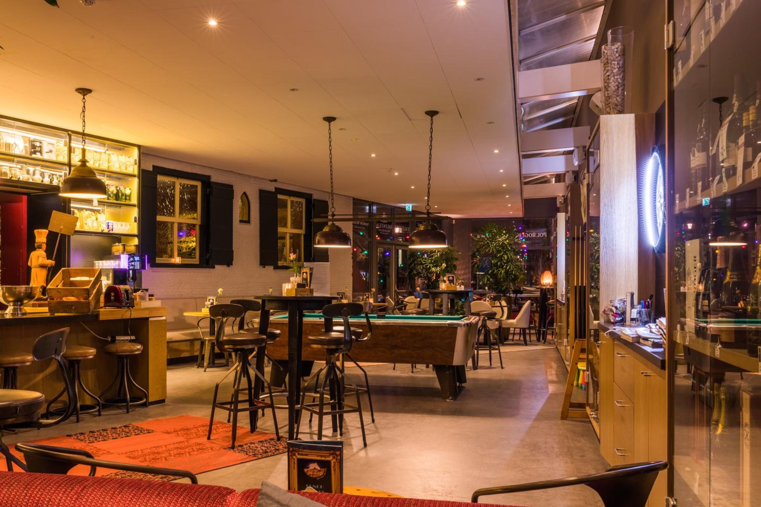 Un espacio interior bien iluminado con mesa de billar, zona de bar y asientos.
