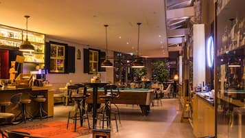 Un espacio interior bien iluminado con mesa de billar, zona de bar y asientos.
