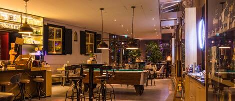 A well-lit indoor space with a pool table, bar area, and seating.