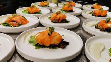 A series of white plates with salmon appetizers, garnished with green leaves and a decorative element.