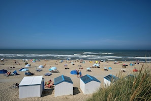 A beach with tents, umbrellas, and beach chairs. - Van der Valk Hotel Texel (De Koog)