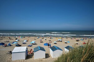 A beach with tents, umbrellas, and beach chairs.