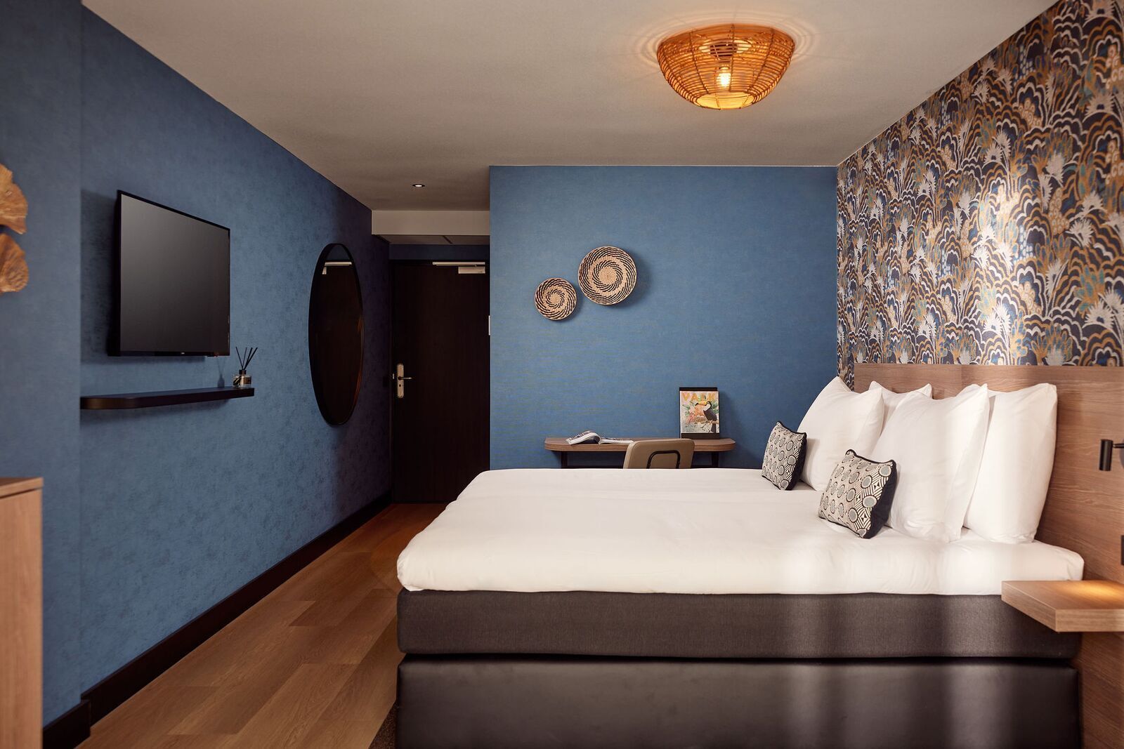 Ein modernes Schlafzimmer mit einem großen Bett, einem Fernseher an der Wand und einem kleinen Tisch mit einem Bilderrahmen.