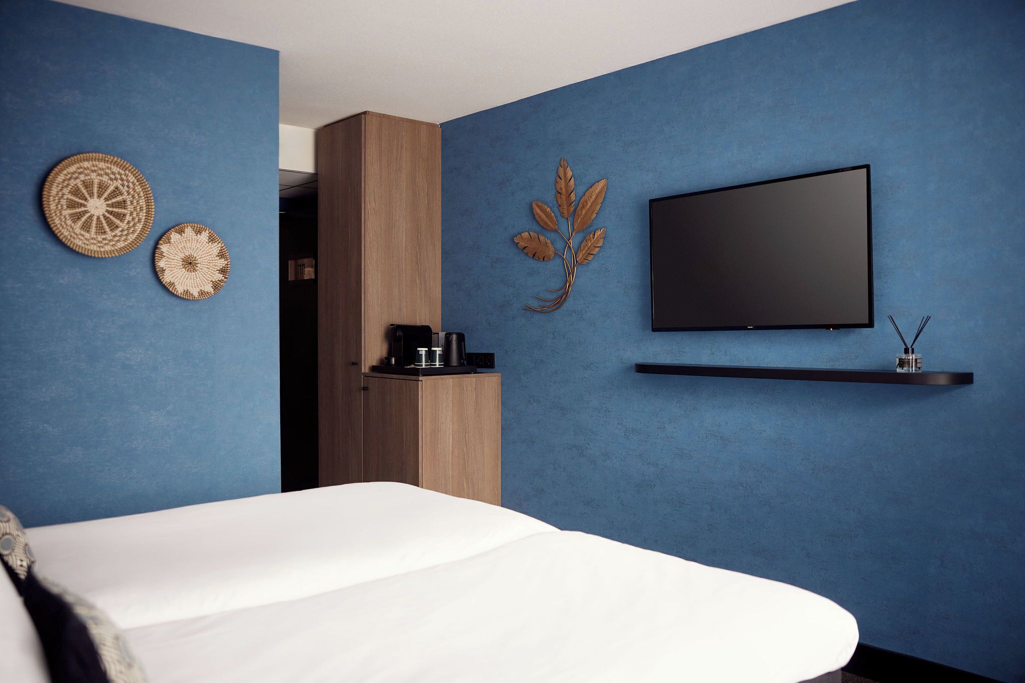 A modern bedroom with a bed, a television, and decorative wall art.