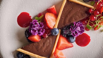 A dessert with chocolate, strawberries, blueberries, and flowers on a plate.