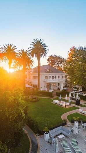 A large white building with a central courtyard, surrounded by palm trees and a well-maintained lawn. - Palm House Boutique Hotel and Spa (Cape Town)