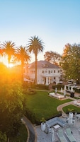 A large white building with a central courtyard, surrounded by palm trees and a well-maintained lawn.