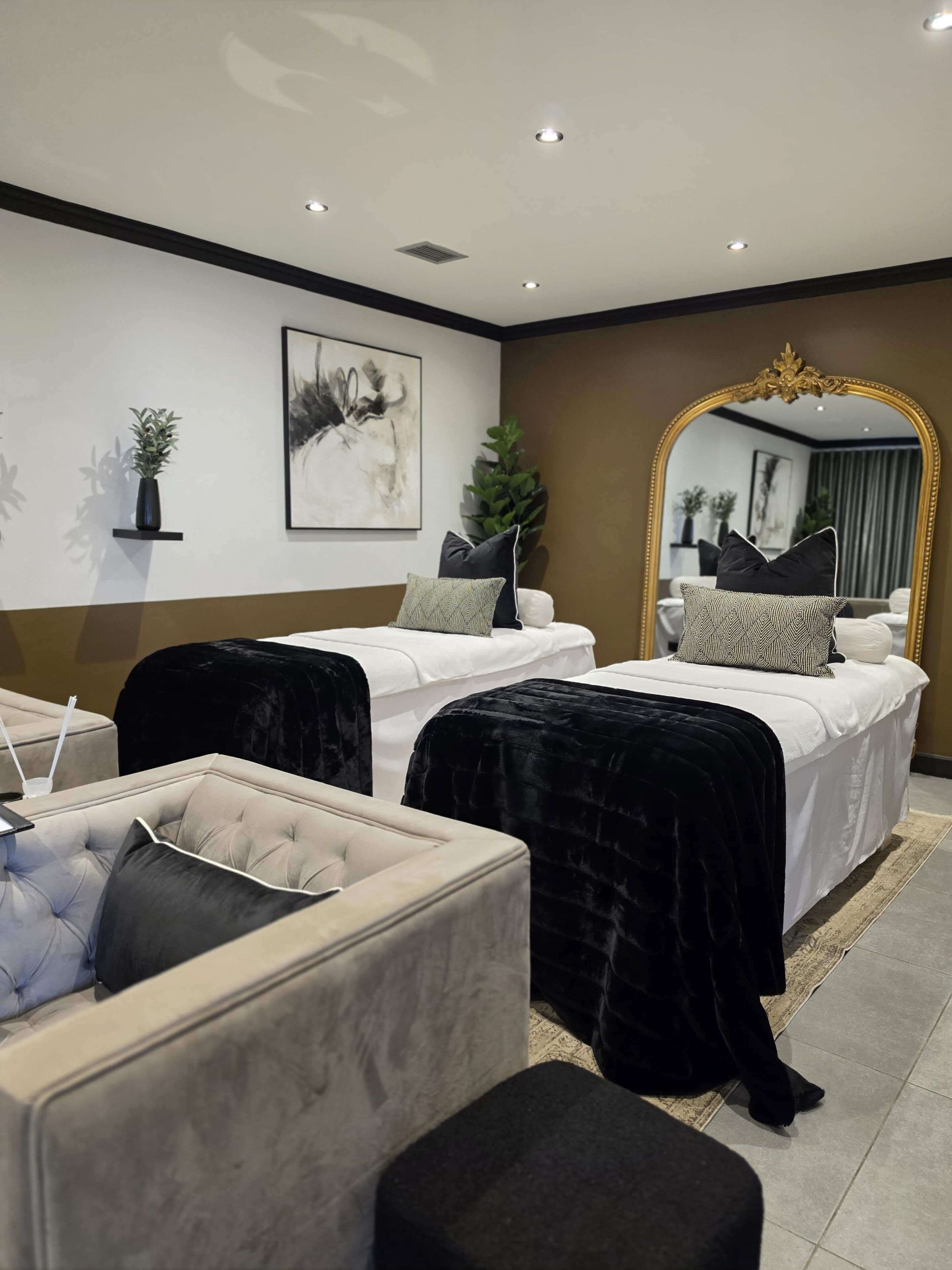 Un dormitorio moderno con dos camas, un espejo grande y una zona de estar.