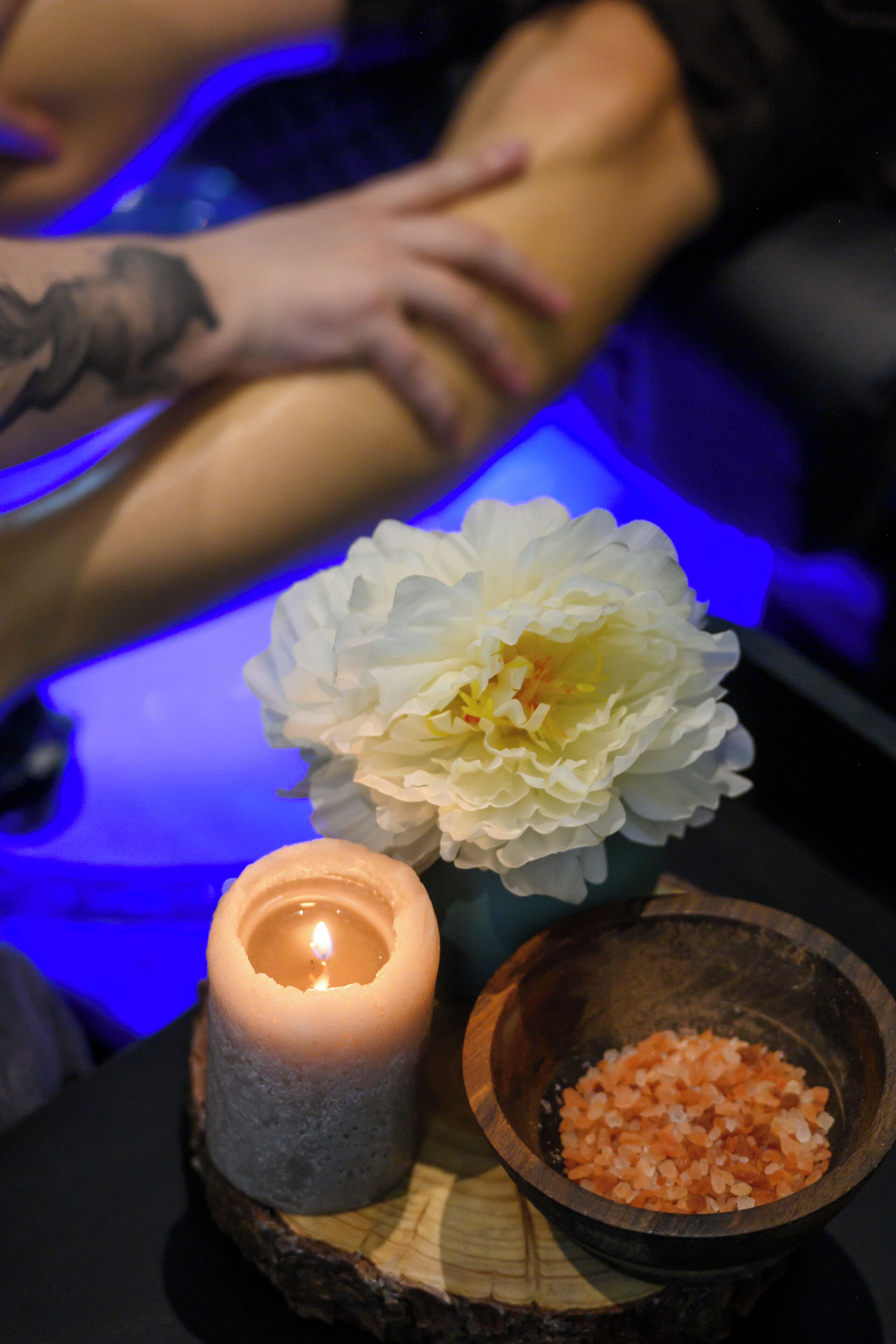 A candle, a bowl of salt, and a flower on a wooden surface.