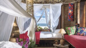 A room with a bed, a small table, and a view of the ocean. - Rancho do Peixe (Cruz)