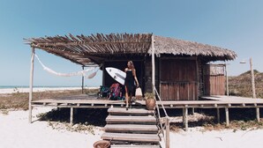 A wooden structure with a thatched roof, a wooden deck, and a beach view. - Rancho do Peixe (Cruz)