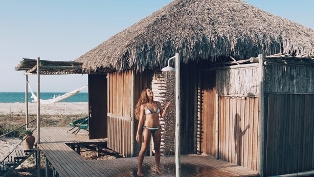 A wooden hut with a thatched roof, a wooden deck, and a hammock on the beach. - Rancho do Peixe (Cruz)