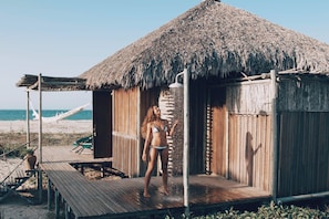 A wooden hut with a thatched roof, a wooden deck, and a hammock on the beach. - Rancho do Peixe (Cruz)