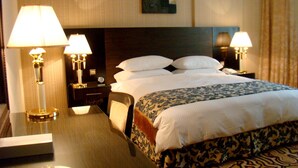 A hotel room with a large bed, two bedside lamps, a nightstand, a chair, and a table with a lamp. - Sharjah Palace Hotel (Sharjah)